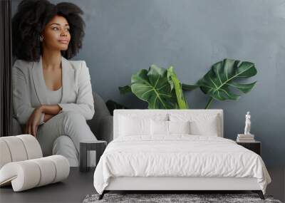 Confident african american woman in white suit seated in modern office lobby surrounded by lush green plants indoor Wall mural