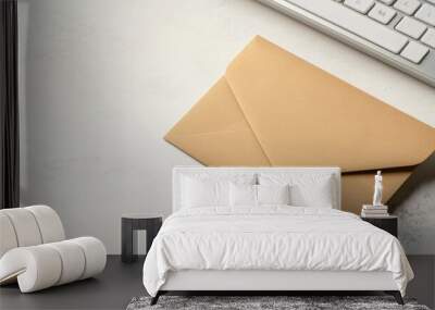 Open brown paper envelope revealing contents next to a sleek white computer keyboard on a clean white table surface. Wall mural