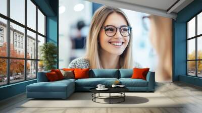 Portrait of a Young Woman Happily Trying on Stylish Eyeglasses at an Optometrist s Office with Modern Frames and Professional Assistance Wall mural