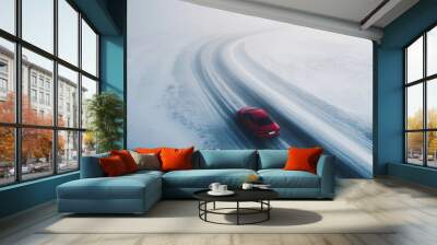 Red car driving on snowy road, winter landscape, aerial view of winding highway with snow-covered surroundings, travel and adventure concept Wall mural