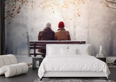 Senior couple in warm clothes seated on wooden bench in winter snowy city park outdoor. Love and relations concept. Wall mural