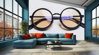 Stylish round eyeglasses with beige glass and blue light reflections isolated on white background closeup Wall mural