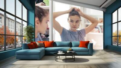 young teen girl straightens her hair looking at her reflection in the mirror Wall mural