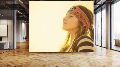 Young woman in a bandana gazes upward as the sun sets, casting a beautiful golden glow Wall mural