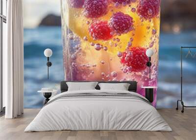 A glass of colorful drink with raspberries and blueberries on the beach. The drink is a mix of blueberry and raspberry juice Wall mural