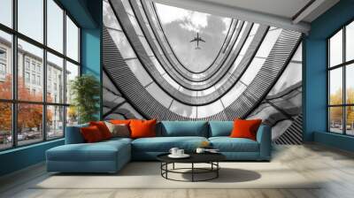 Flying airplane and modern architecture building, low angle black and white abstract looking picture  Wall mural