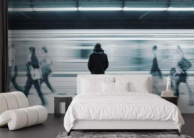 Long exposure of lonely man at subway station with blurry train and walking people Wall mural