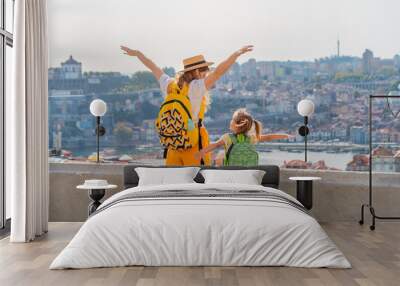 View from behind of Young red-haired mother and little daughter raised thair hands up against the Porto city, Portugal Wall mural