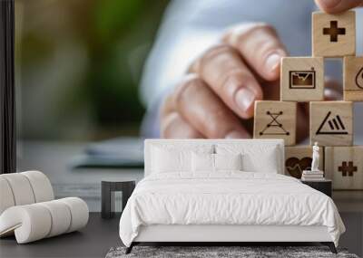 Hands stacking healthcare-themed wooden blocks on a table, symbolizing health and medical concepts. Wall mural