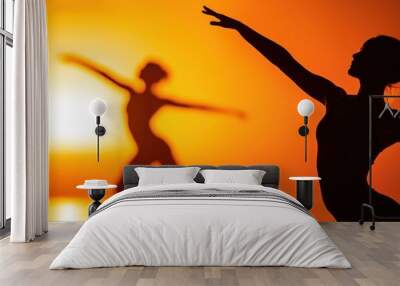 Silhouette of dancers performing at sunset, capturing grace and movement in an enchanting orange glow. Wall mural