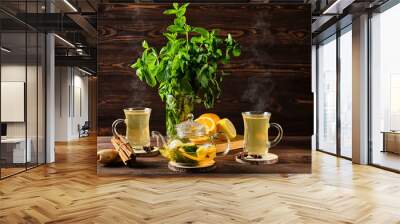 Citrus tea with ginger and mint leaves in a glass teapot, dark food photography. Wall mural