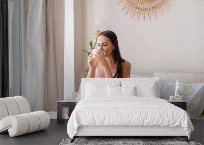 Cute girl drinking tea in bed in sunny morning Wall mural