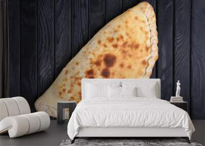 Fresh baked pizza calzone on dark wooden table, top view. Wall mural