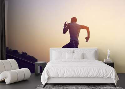 A strong young man is running in the evening. Wall mural