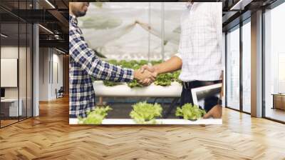 Organic vegetable growers shake hands with customers in the hydroponics vegetable garden after negotiating a successful. Wall mural