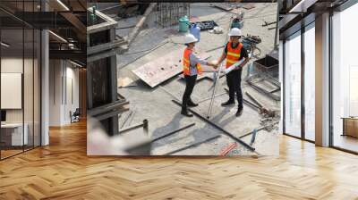 Two construction engineers shake hands in construction site Wall mural