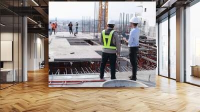 Two engineers work on the construction site. They are checking the progress of the work. Wall mural