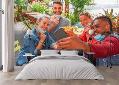 Friends taking selfie in a bar restaurant with face mask on in coronavirus time - Young people having fun with drinks and snacks outside with new rules after virus break Wall mural