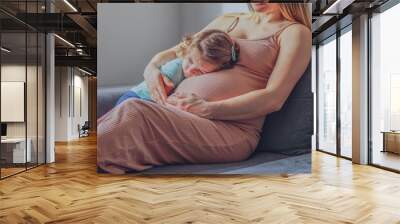 Little baby girl relaxing on mom's pregnant belly - Pregnant mother with a toddler - Family concept Wall mural