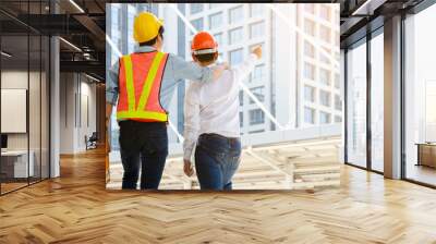 Back view engineer and technician foreman with hardhat helmet working together and viewing building in modern city. Construction, engineering and teamwork concept. Wall mural