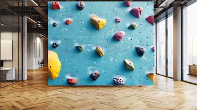 Colorful climbing wall holds on a blue indoor bouldering surface, ready for rock climbing enthusiasts. Wall mural