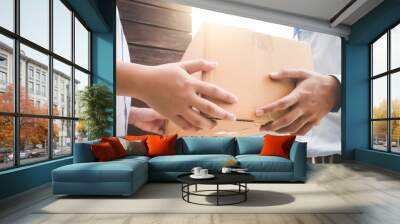 Close up hand of asia woman are receive a box from delivery man with sun light in delivery service concept. Wall mural