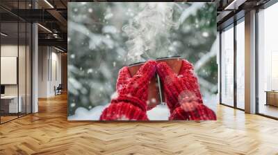 A pair of red mittens holding onto a steaming thermos of soup surrounded by evergreen trees dusted in powdery snow Wall mural