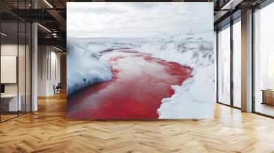 A river flowing through a snowy landscape, appearing red, creating a striking contrast with the white surroundings. Wall mural