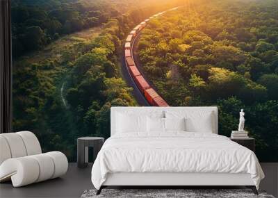 Aerial view of a vibrant cargo train snaking through a lush green landscape at golden hour Wall mural