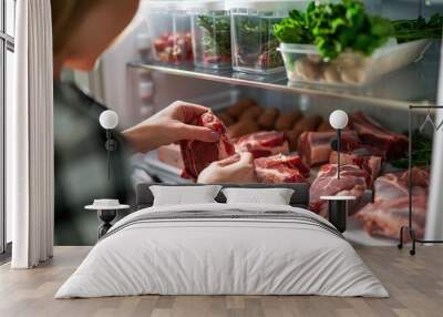 Woman putting raw meat in refrigerator, closeup, Refrigerator with fresh meat products Wall mural