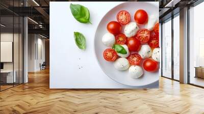 Fresh caprese salad with cherry tomatoes, mozzarella, and basil on white plate Wall mural