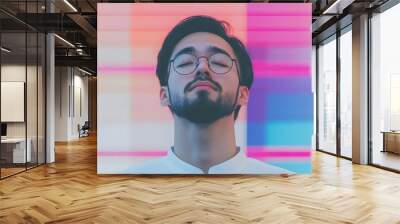 Serene young man with glasses against vibrant geometric background Wall mural