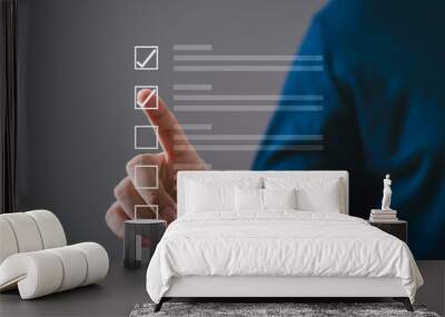 Person tapping virtual checklist on transparent screen, symbolizing tasks, productivity, and digital organization on a solid background. Wall mural