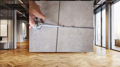 The hand of a construction worker filling the gap between ceramic tiles with silicone Wall mural