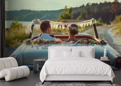 Newlyweds driving away in a vintage car decorated with ribbons. Wall mural