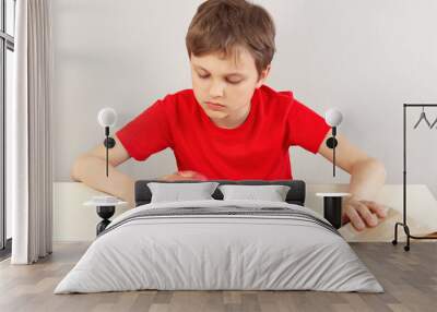 Young boy at the table chooses between hamburger and apple on a white background Wall mural