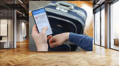 Flight cancelled. Smartphone application announces bad news to tourist. Man holding mobile phone in hotel room. Smart phone with flight cancelled concept on screen.  Wall mural