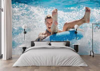 Funny girl taking a fast water ride on a float splashing water. Summer vacation with water park concept. Wall mural