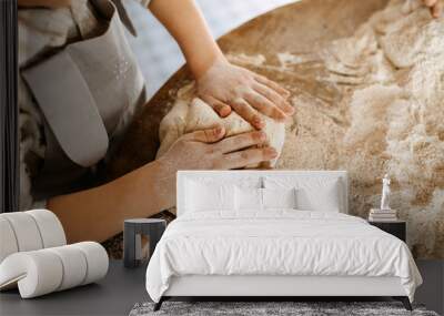 Child making dough for bread, mixing flour on a wooden table surface. Wall mural