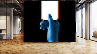 Doctor's hand in medical gloves holding phone isolated on black Wall mural