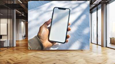 A Mockup of a blank iphone screen. A hand holding the phone plain background Wall mural