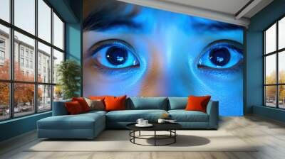 A woman with dark eyes staring at the camera. The blue light in the background adds to the mood of the image Wall mural