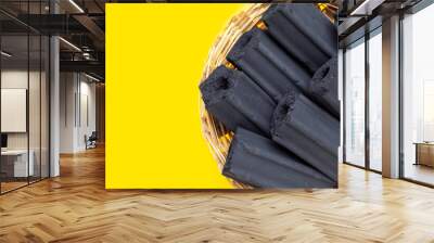 Non smoke wood charcoal in bamboo basket on yellow background. Wall mural