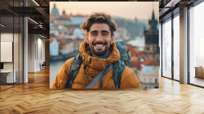 Happy male traveler wearing casual outdoor attire posing with a historical city view behind him Wall mural