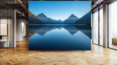 Reflection of majestic mountains on a calm lake in the morning under a blue sky Wall mural