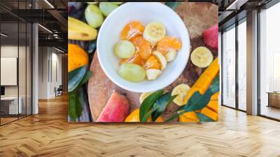 Apples, tangerines, bananas, mangoes and grapes on a wooden boar Wall mural