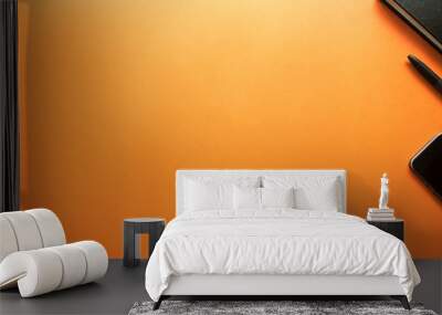 black pen and smartphone with notebook on orange background Wall mural