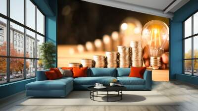 Hand holding a light bulb with coins stack. Creative ideas for saving money concept. Money management for the future Wall mural