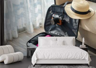 An open tourist suitcase with camera and hat with packed cloths for travelling. Conceptual of travel and holiday background. Wall mural