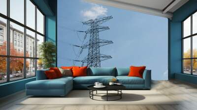 A beautiful large steel high voltage electric tower stands on a background of blue sky Wall mural